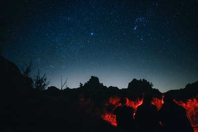 夜空下，三个人坐在篝火前的剪影照片